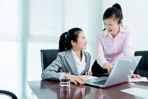 Two businesswomen working together on laptop.